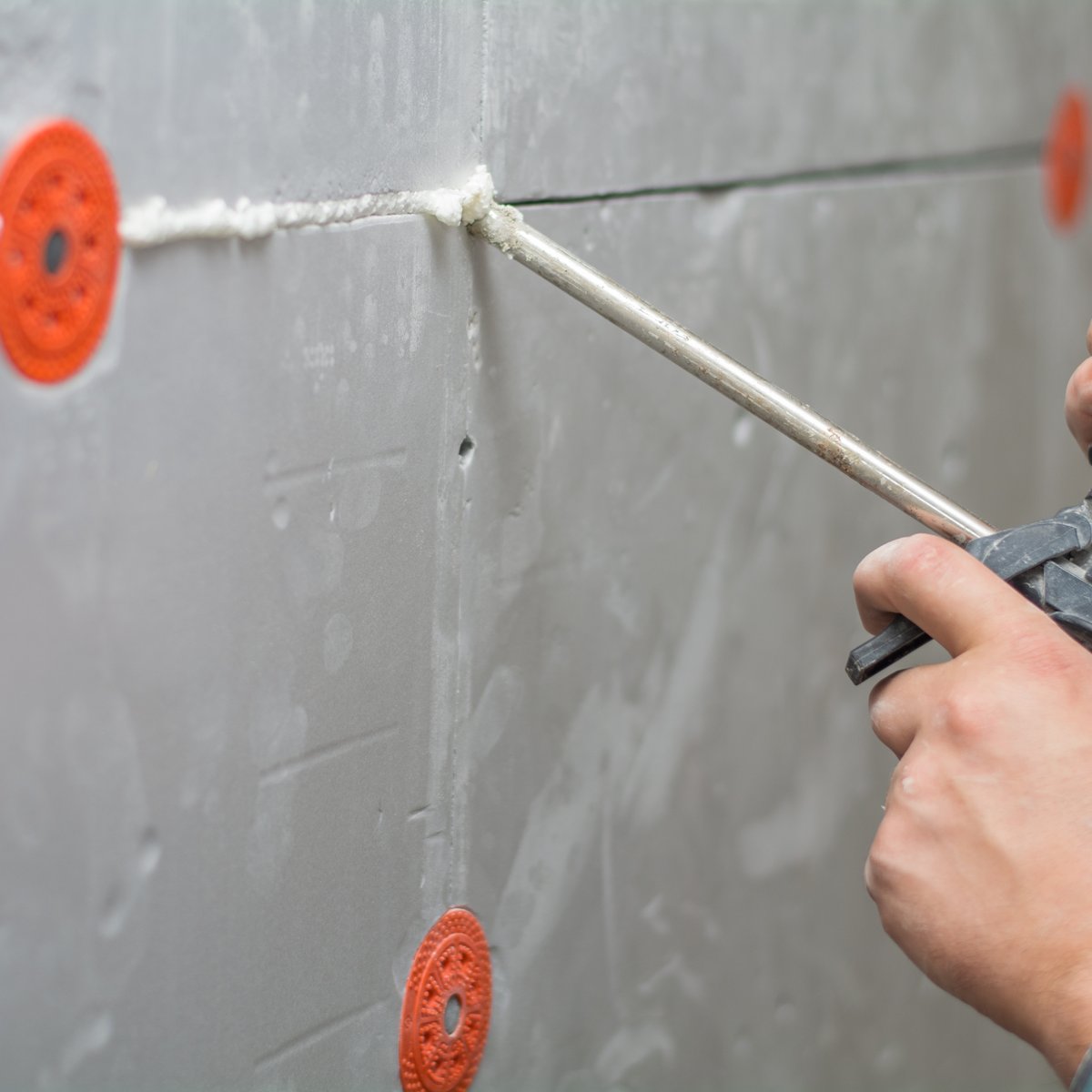 Worker applying sealant with a gun along the joint between wall boards - caulking and sealant joint service in Chicago, IL by MasonryPros.us