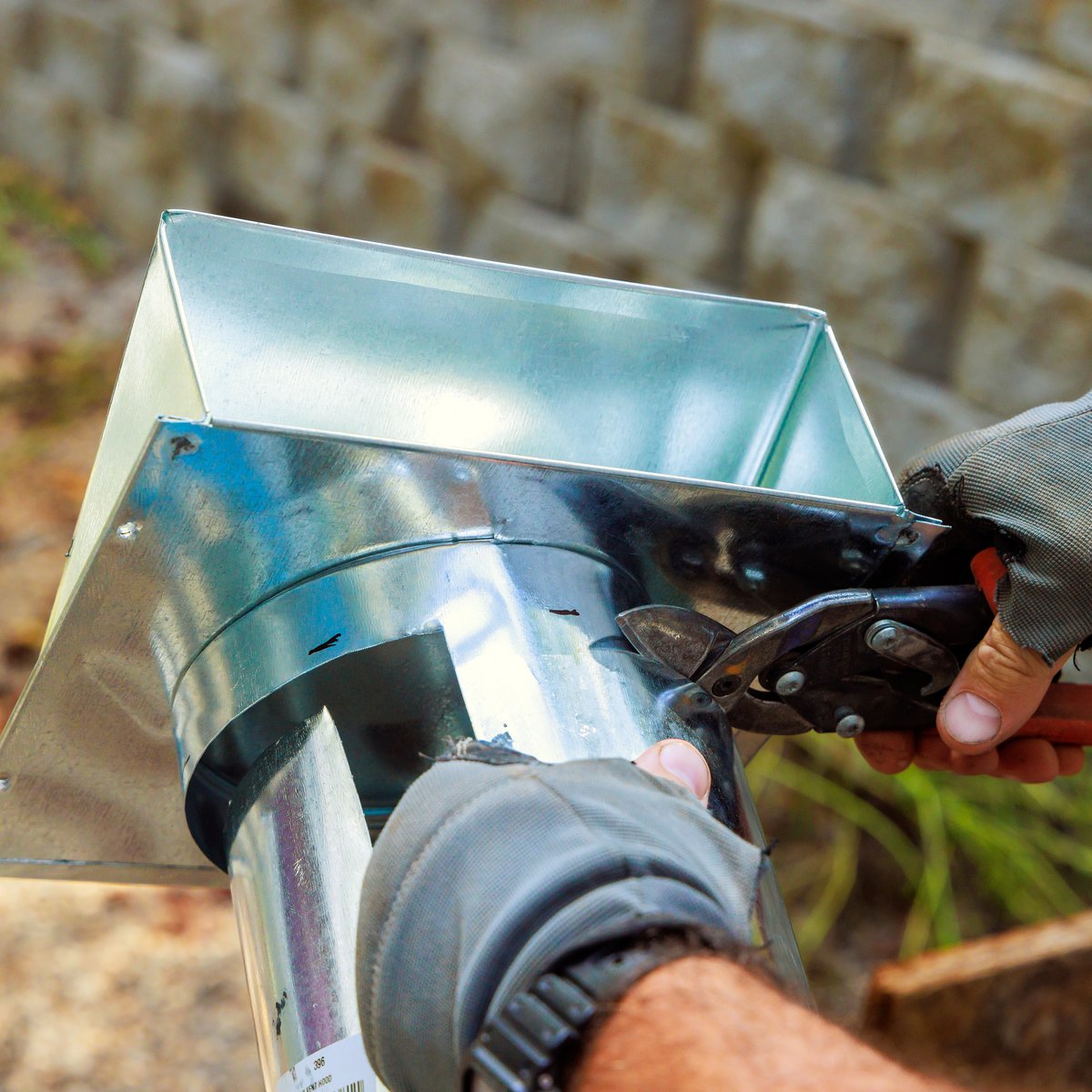 Gloved worker cutting galvanized sheet-metal flashing for a chimney flue liner with tin snips - chimney relining in Chicago, IL by MasonryPros.us