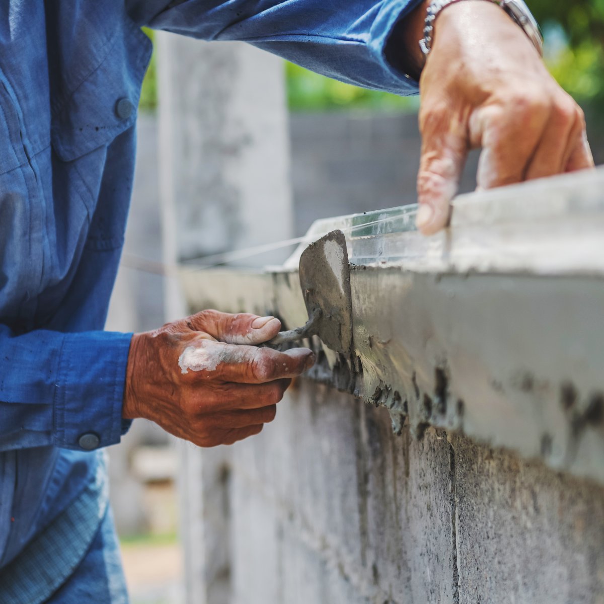 Mason troweling fresh mortar along the capstone of a block parapet wall - parapet wall repair in Chicago, IL by MasonryPros.us