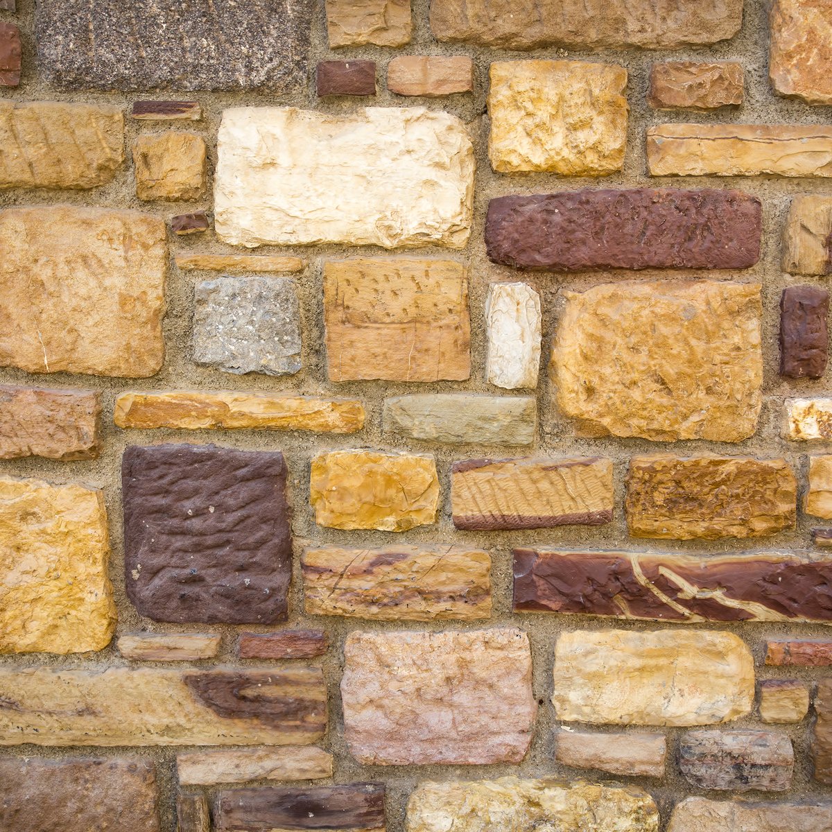 Natural stone wall of mixed golden, brown and grey fieldstone set in mortar - custom stone masonry in Chicago, IL by MasonryPros.us