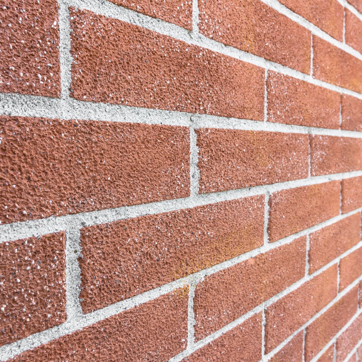 Close-up of a Chicago red brick wall in sharp perspective with freshly repointed pale mortar joints - professional tuckpointing and repointing by MasonryPros.us masons in Chicago, IL